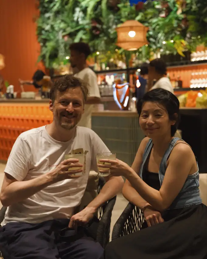 Two guests enjoying drinks beside the warmly lit bar