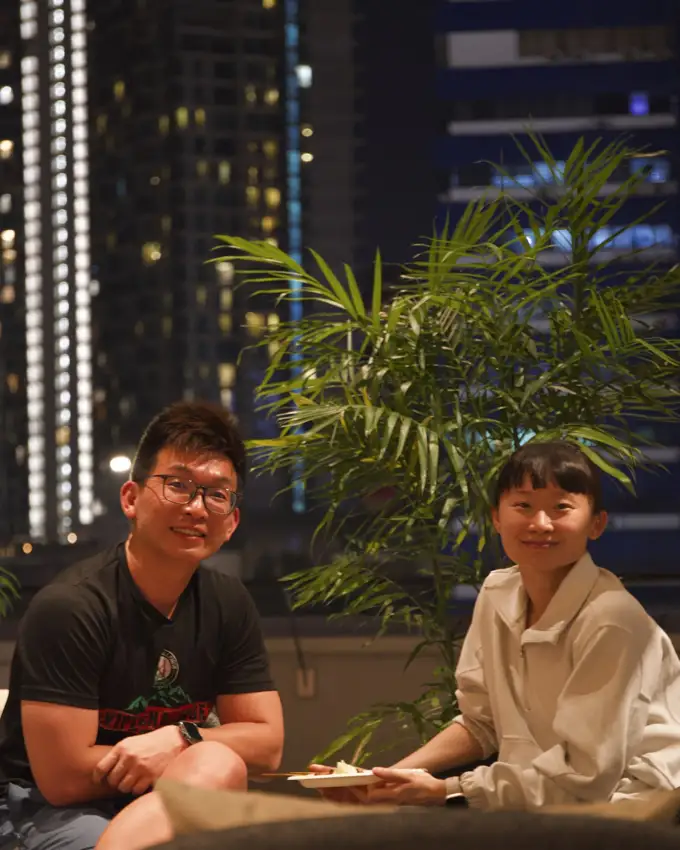 Two guests at Crafty’s with the illuminated Kuala Lumpur skyline behind them